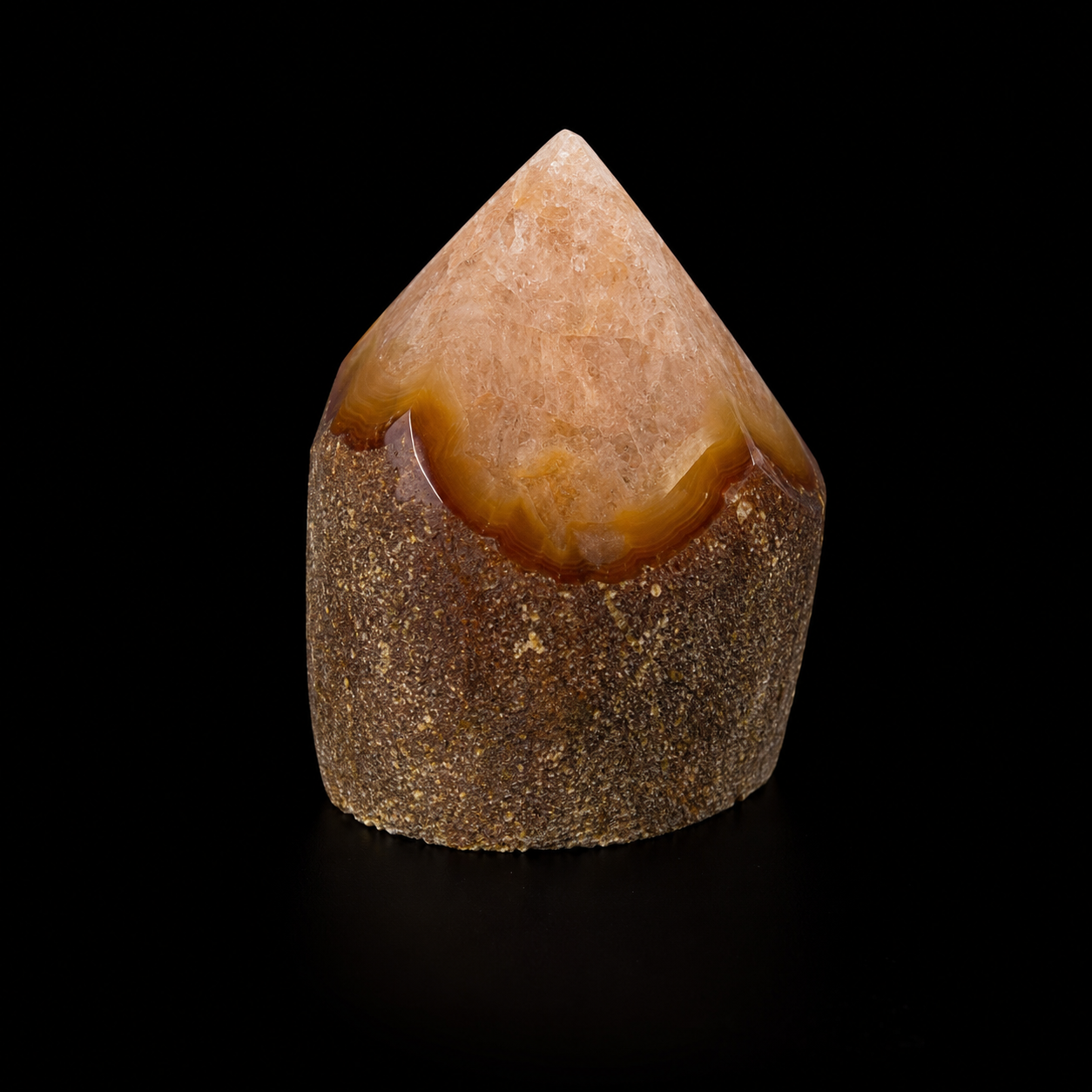Front view of a unique semi-polished agate point with warm natural banding, rough base and polished apex on a black background
