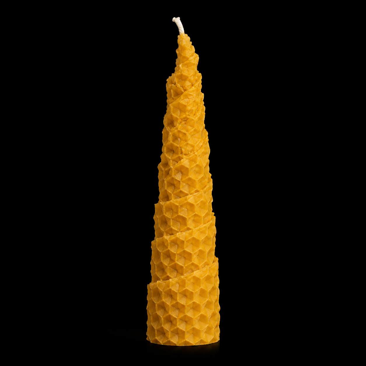 Handmade spiral beeswax honey candle with tapered shape, honeycomb texture and warm golden colour