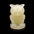 Front view of green onyx owl carving with soft translucent glow on black background