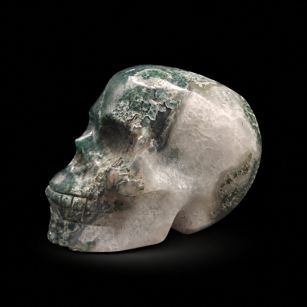 Moss agate skull side view showing green moss-like patterns and translucent white agate areas