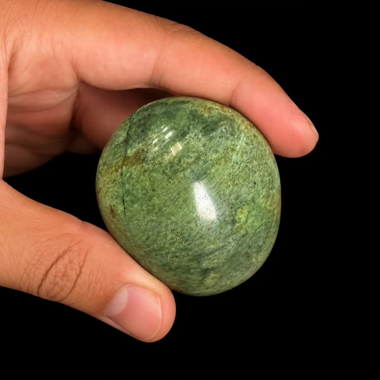 Polished chrysoprase palm stone held in hand as size reference, showing natural green mottled tones, subtle veining and glossy finish