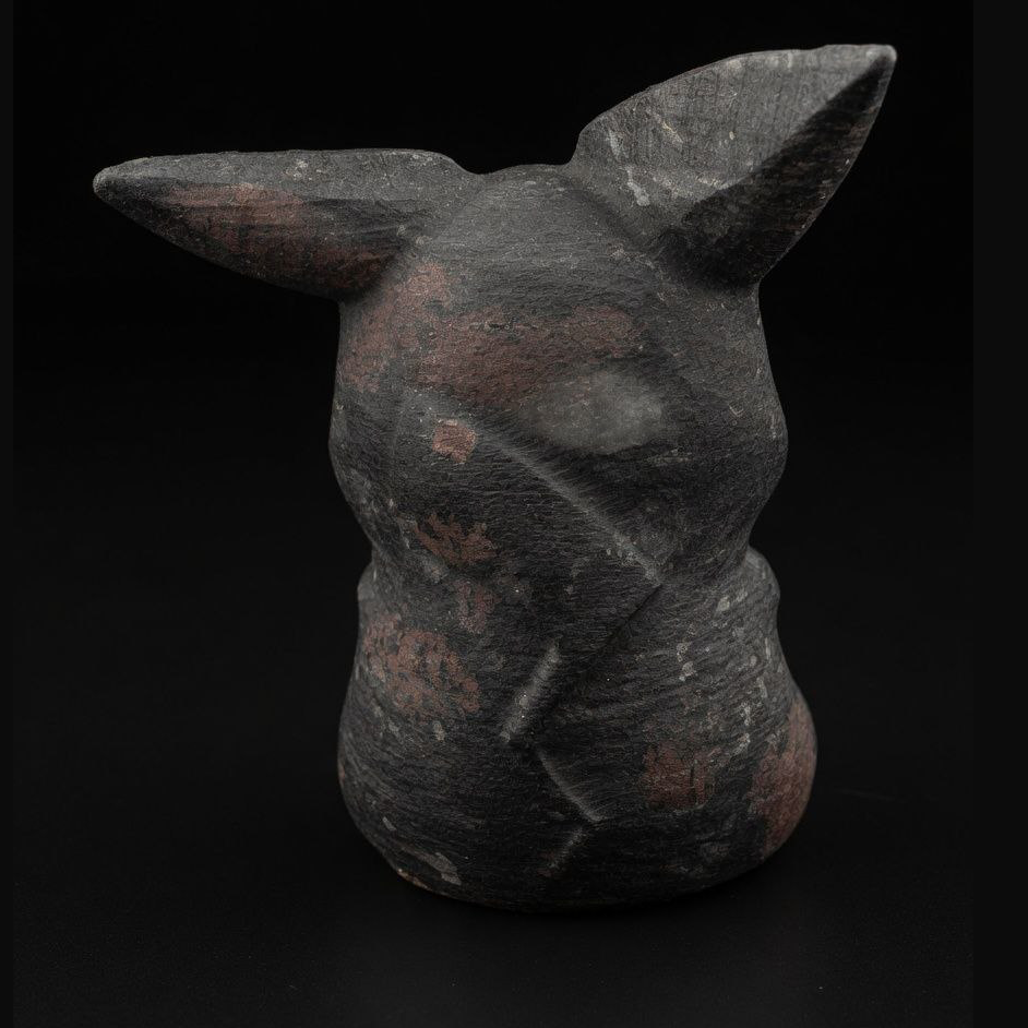 Technical back photograph of the substantial 500g Garnet matrix Pikachu carving, highlighting the continuous mineral texture, natural patterns, and carved ear facets on black background