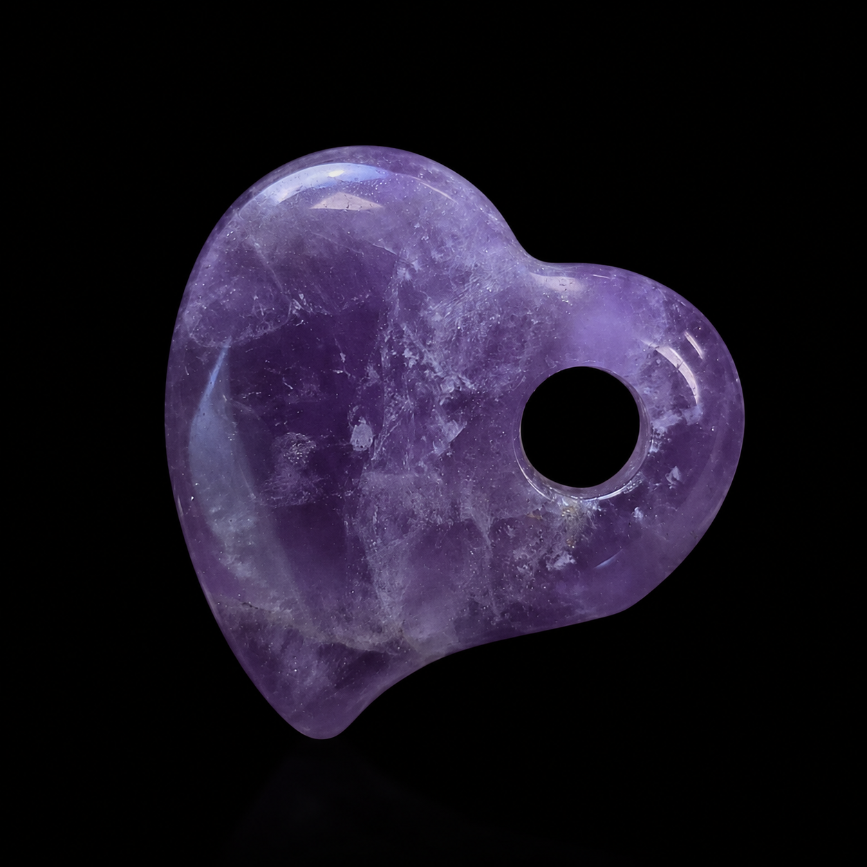 Polished amethyst heart pendant with drilled hole on black background, showing purple colour, natural inclusions and glossy surface