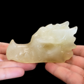 Citrine dragon head carving in hand, opposite side view with polished surface and carved dragon features
