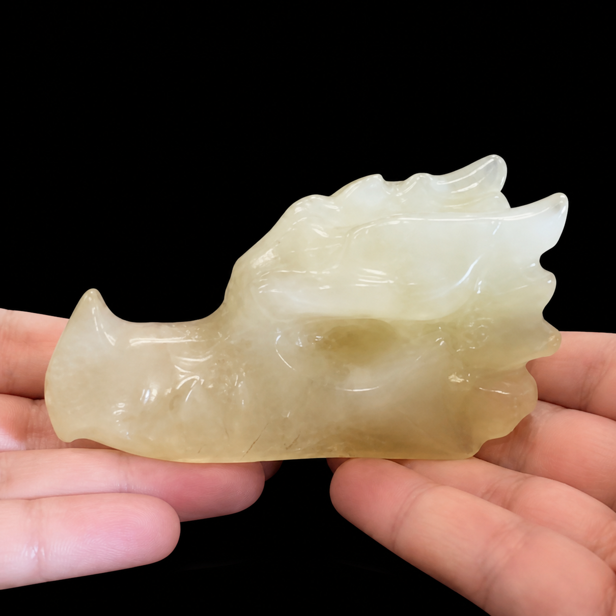 Citrine dragon head carving in hand, opposite side view with polished surface and carved dragon features