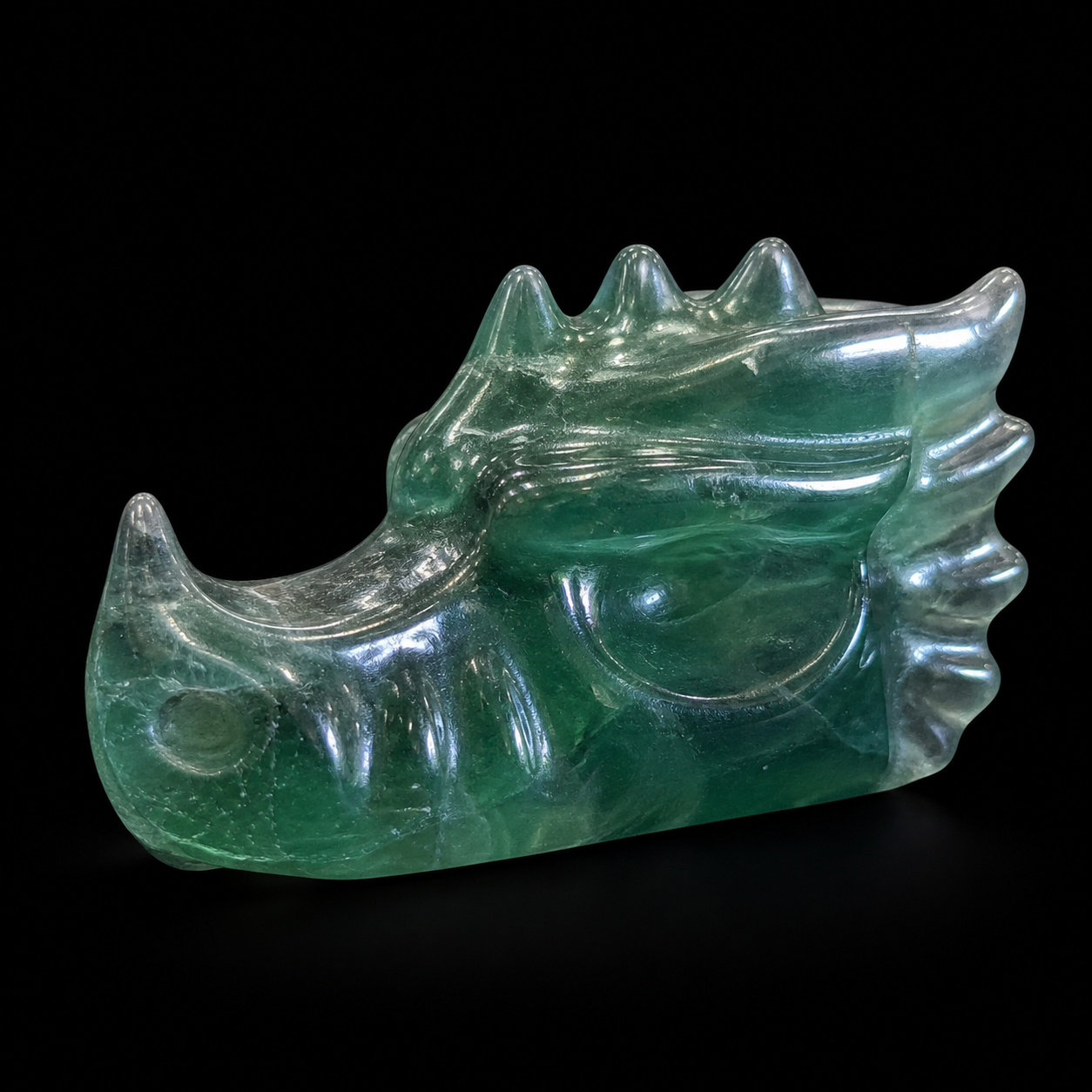Opposite side view of a carved green fluorite dragon with glossy finish and visible internal mineral zoning