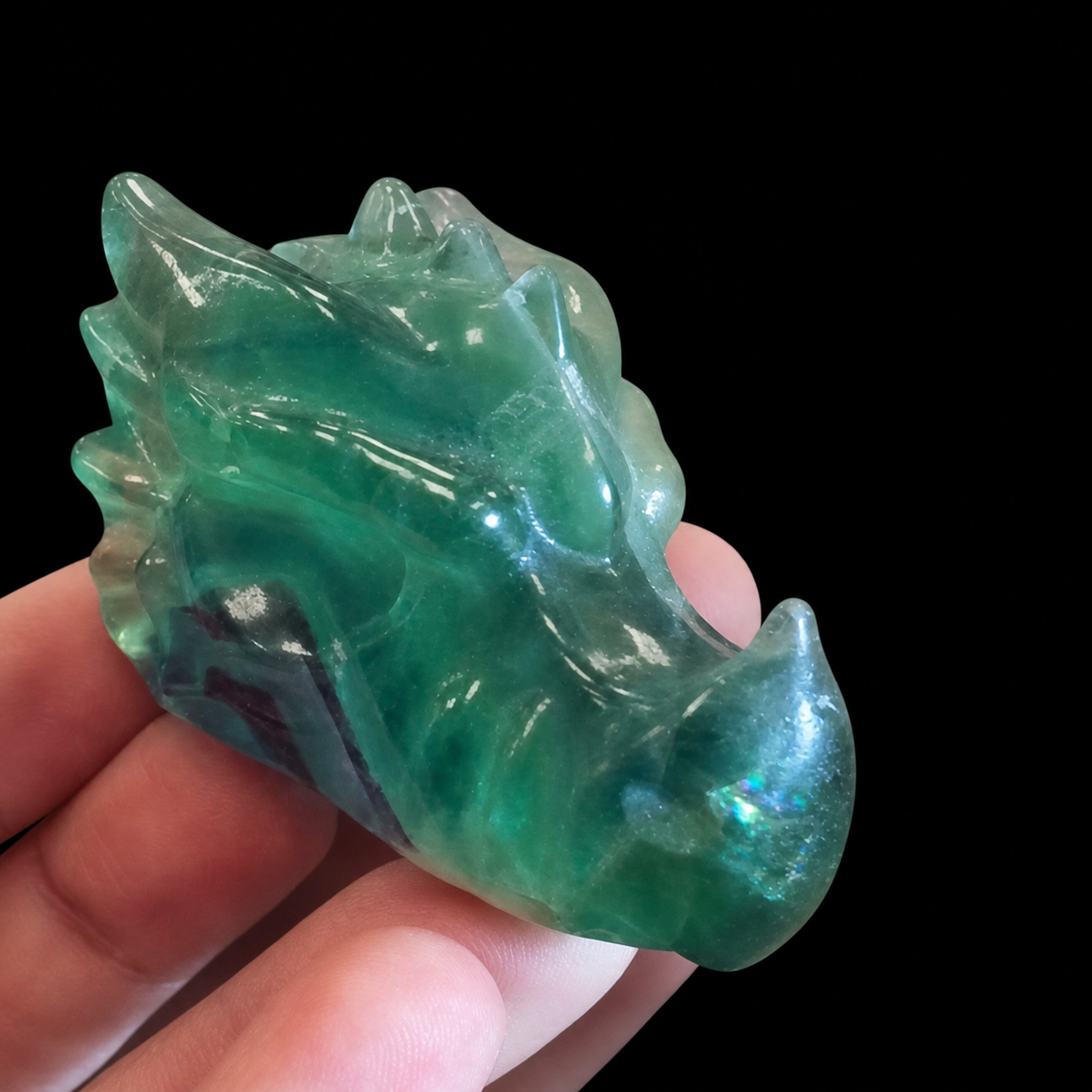 Green fluorite dragon carving side view with translucent body, polished ridges and natural purple zoning