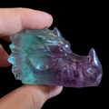 Fluorite dragon head carving side view under lower light showing natural purple and blue-green fluorite tones