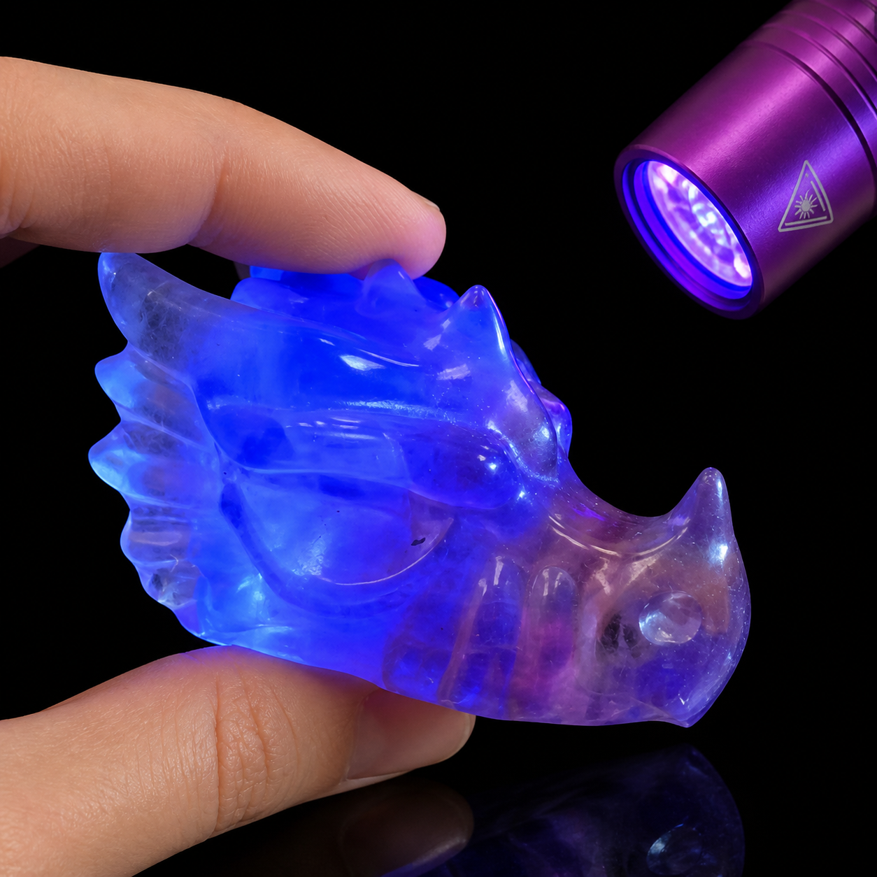 UV reactive fluorite dragon head carving glowing blue-violet under ultraviolet flashlight light
