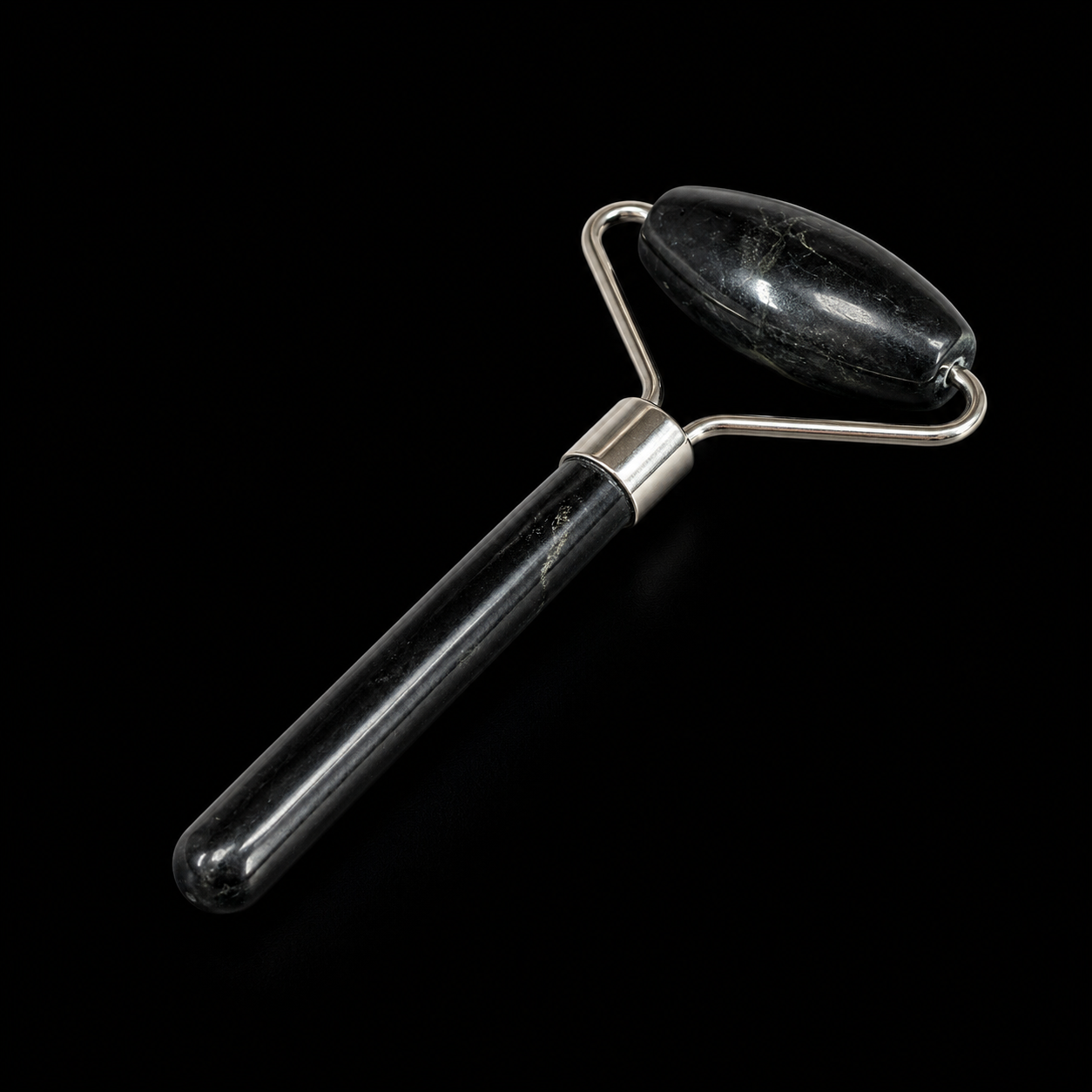 Black onyx facial massage roller with elongated oval roller head and silver-tone fittings on a black background.