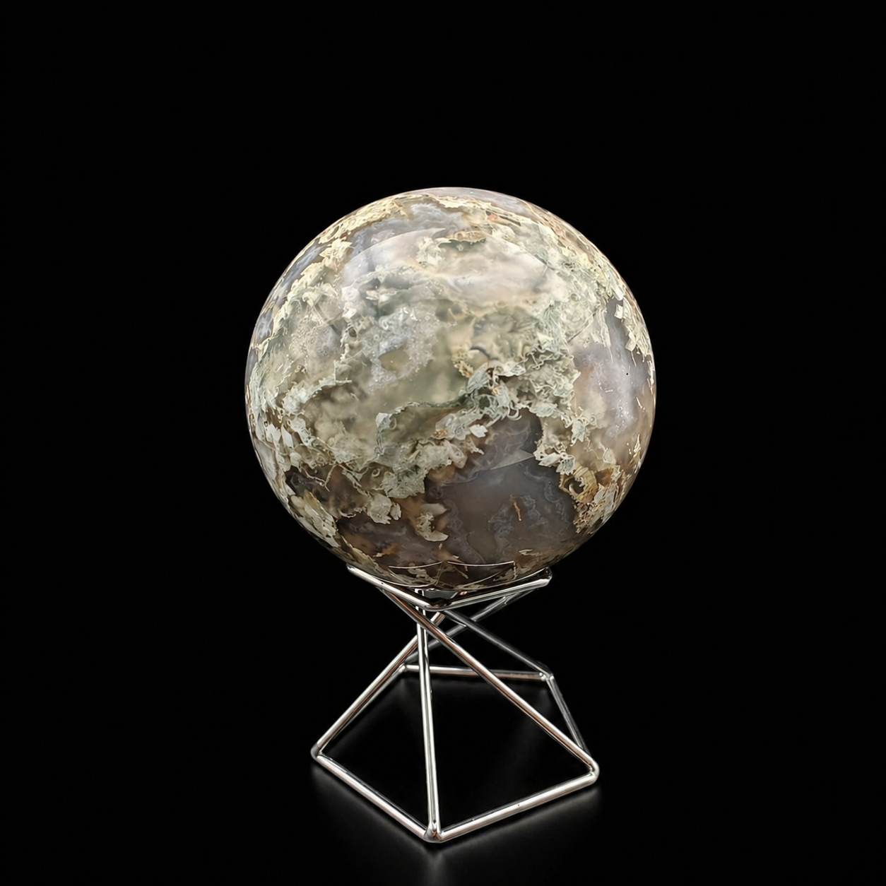 Front view of a polished moss agate sphere 460g with soft green and cream scenic inclusions on a metal stand