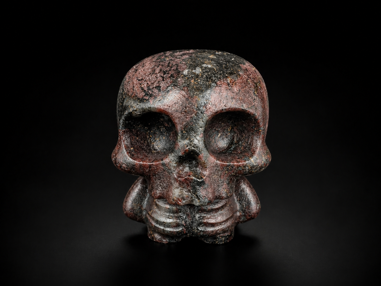 Garnet with astrophyllite skull figure with dark red, black and grey tones and metallic flecks, front view