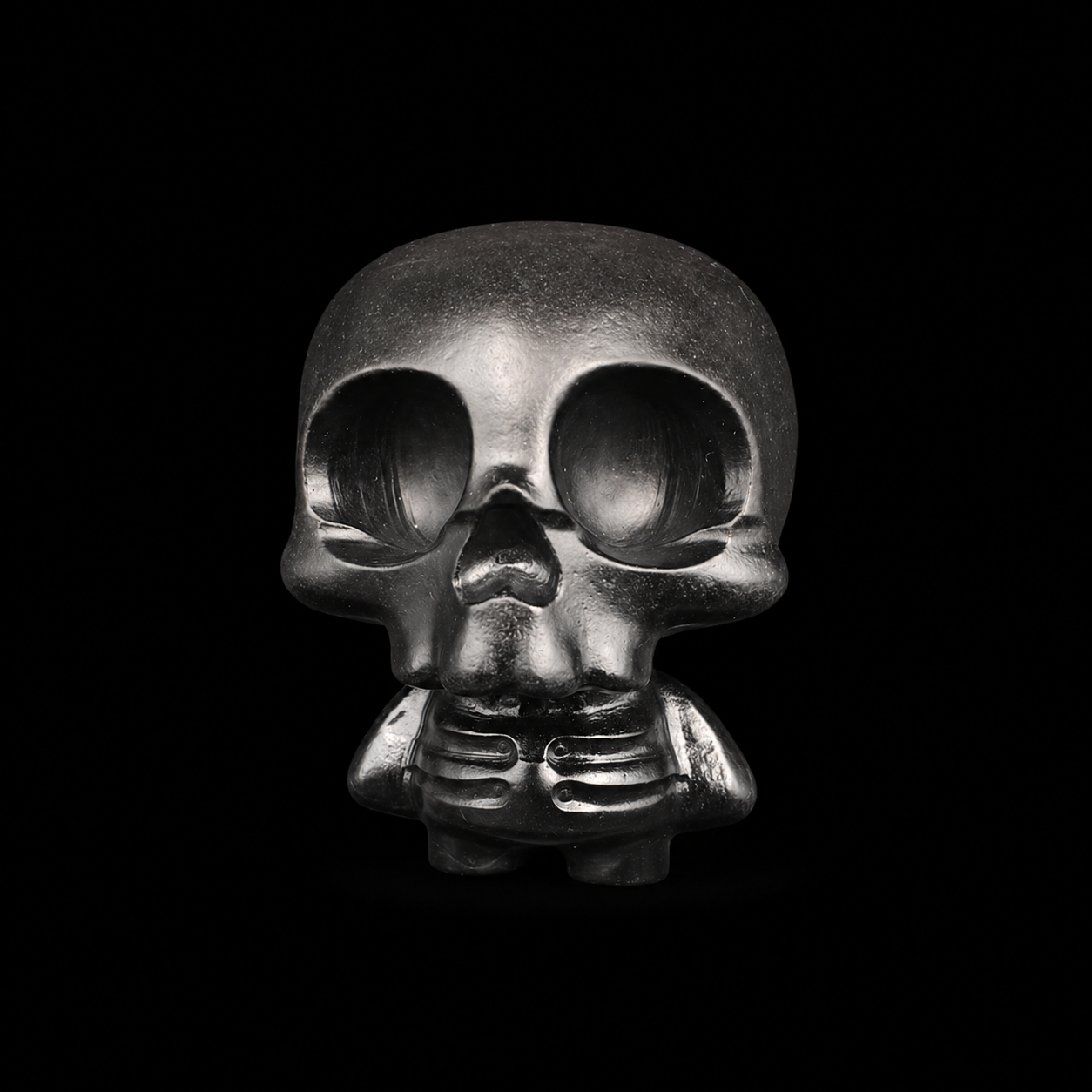 Black obsidian skull figure with large eye sockets, glossy black finish and carved skeleton body, front view