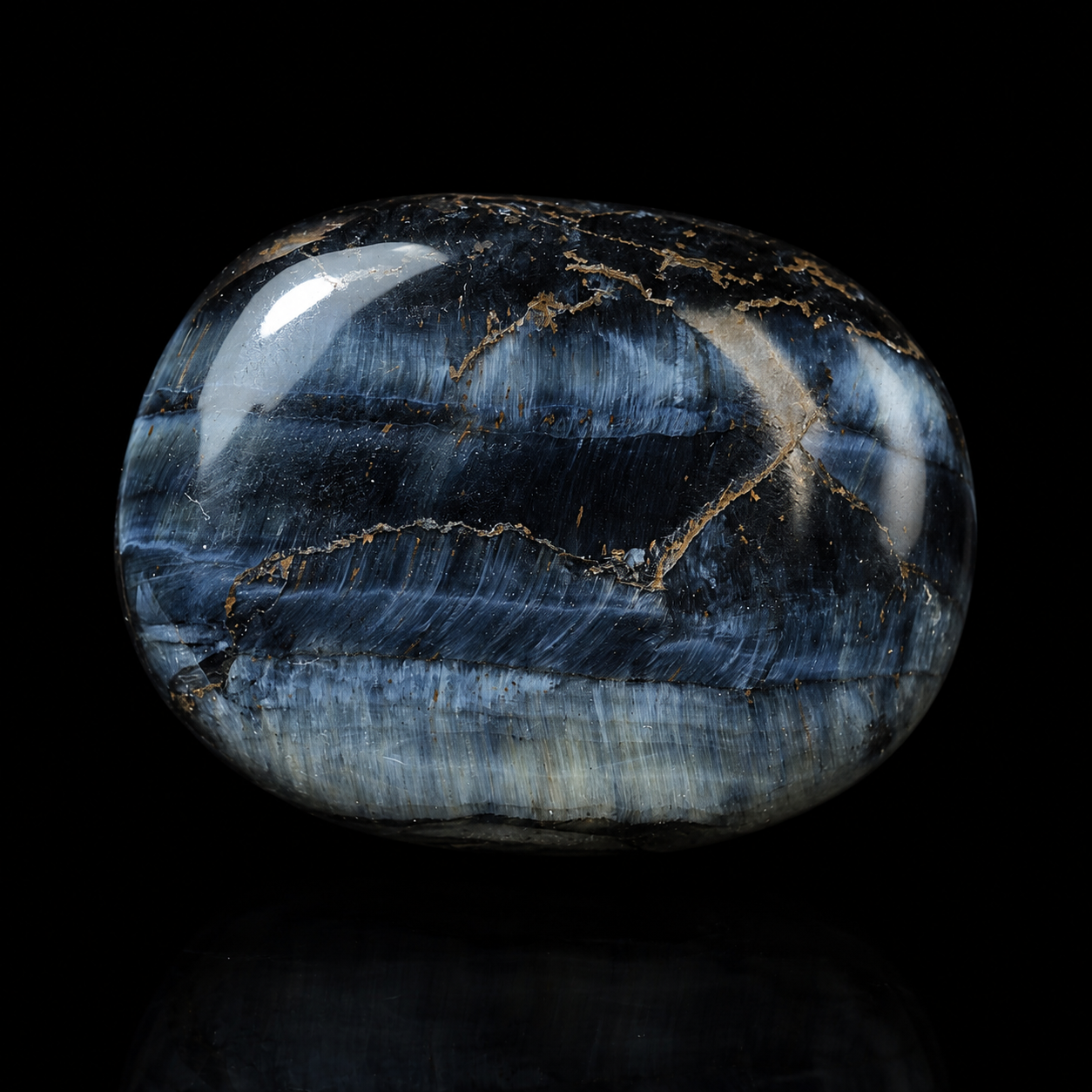 Polished Hawk’s Eye palm stone, close-up detail view showing dark blue-grey chatoyancy, natural golden veining and glossy finish