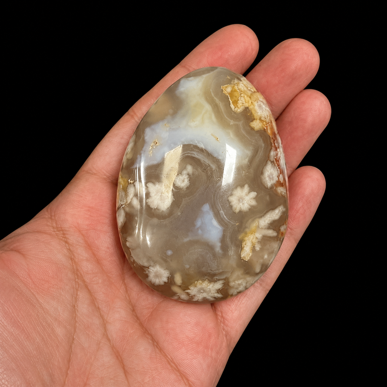 Large Flower Agate palm stone held in hand, showing polished translucent agate with cream floral patterns, honey tones and natural inclusions.
