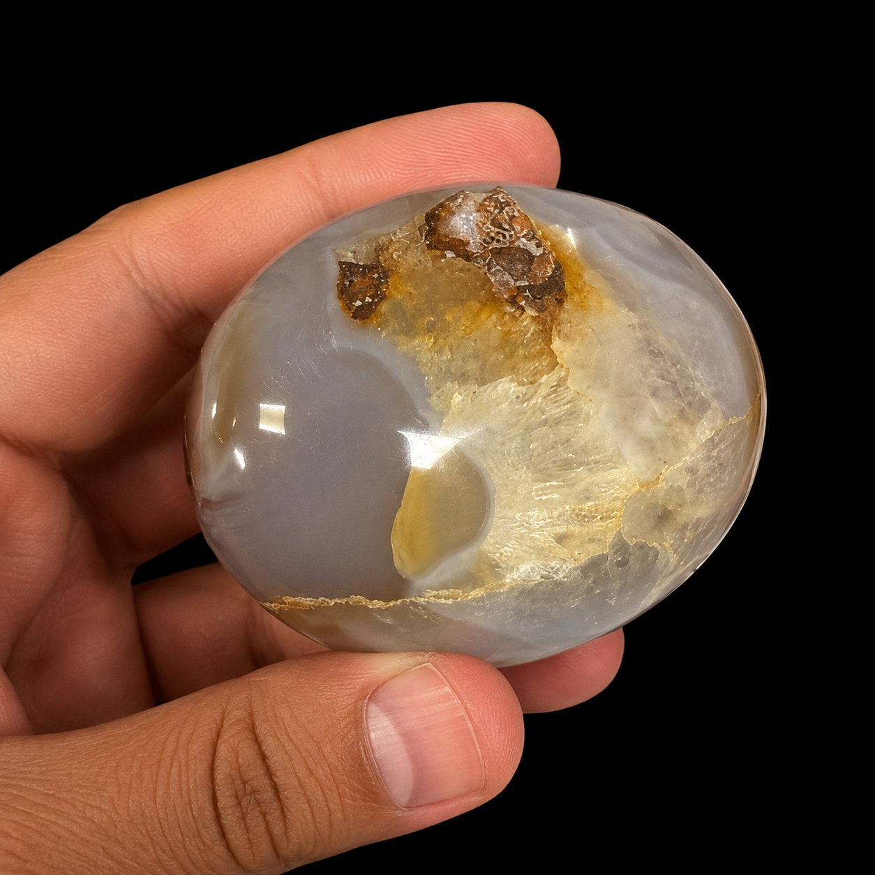 Medium Flower Agate palm stone held in hand, featuring translucent grey-beige agate with white floral inclusions and natural earthy tones.