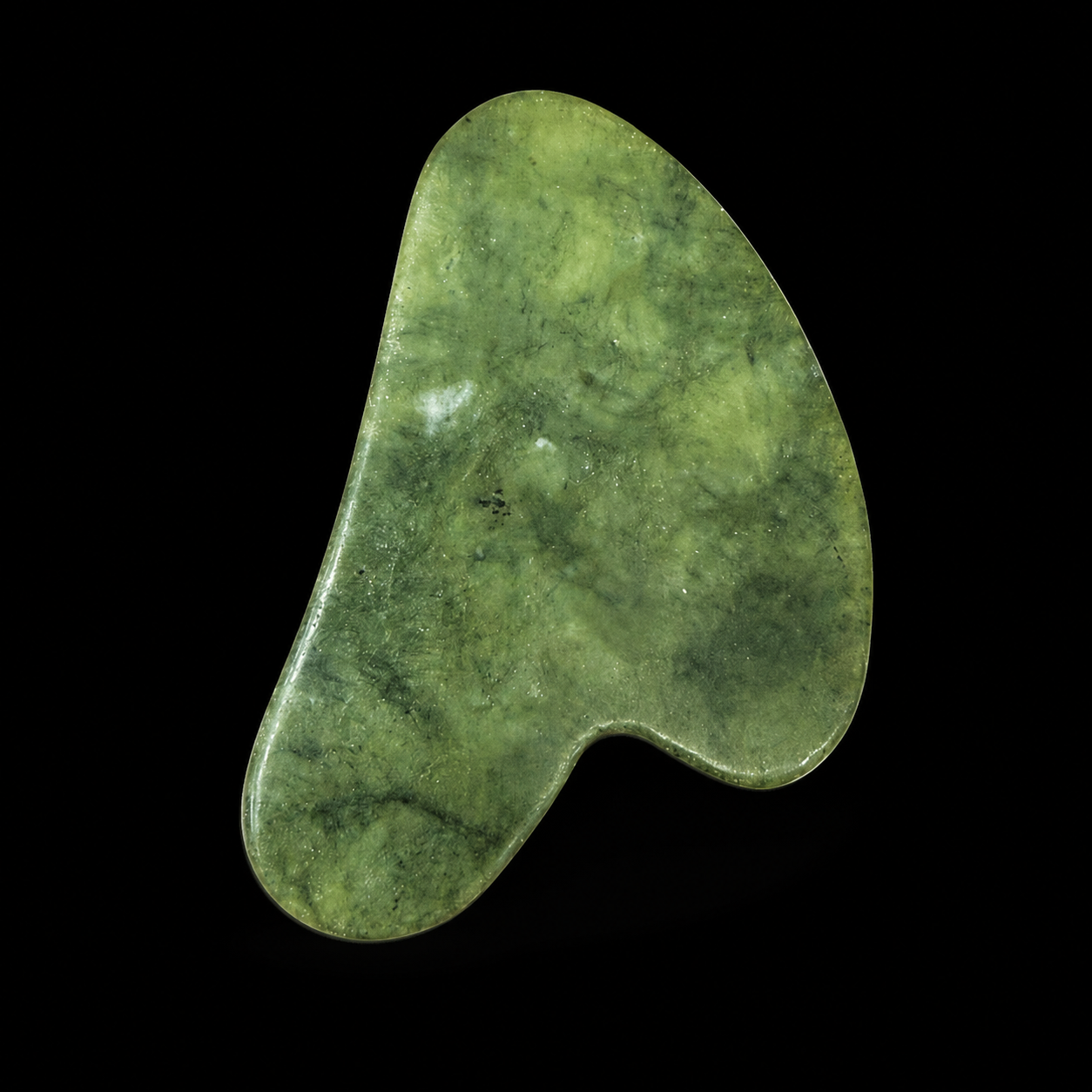 Polished jade Gua Sha tool, front angled view showing natural green mottling, smooth curved massage shape and rounded polished edges.