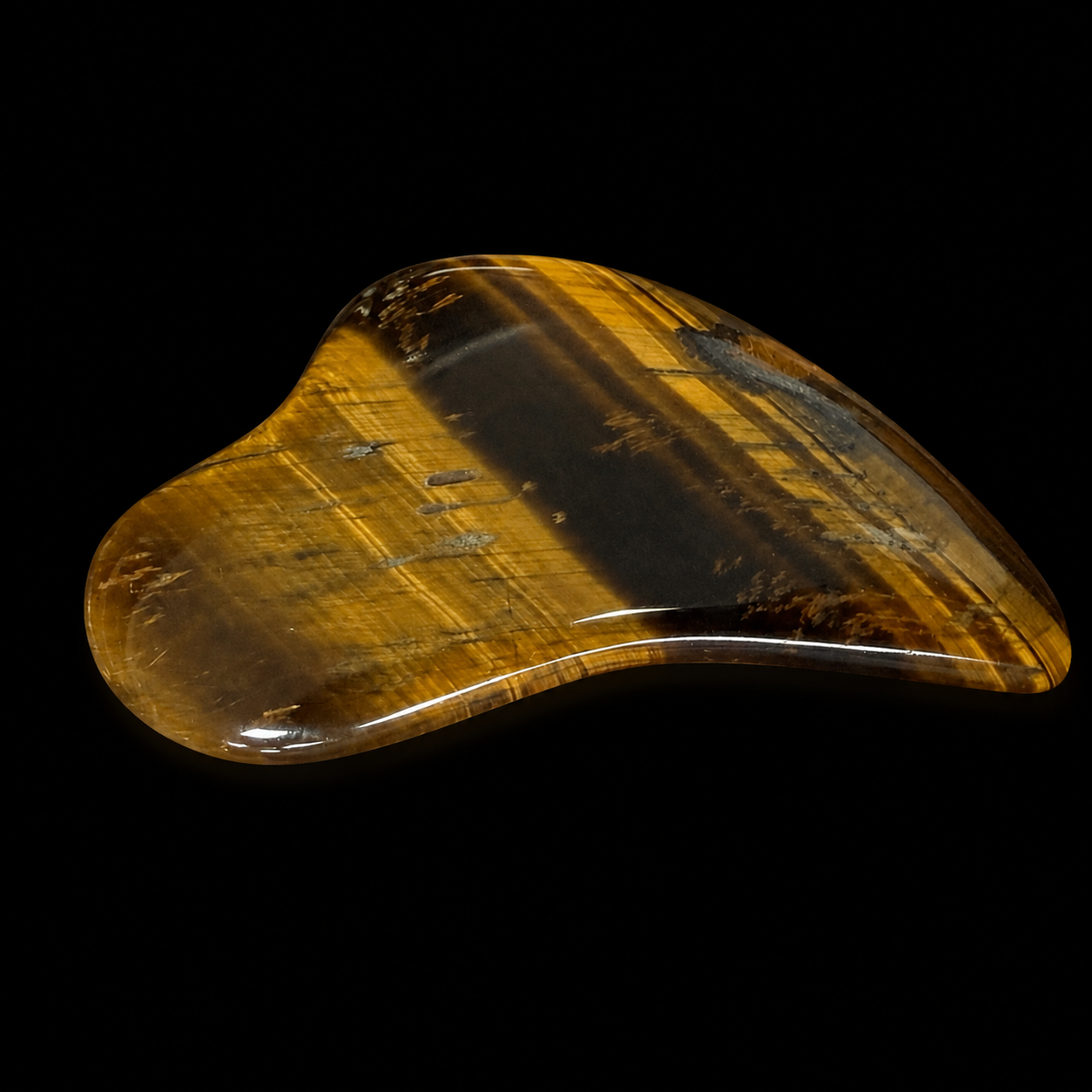 Polished tiger’s eye Gua Sha tool, angled side view showing golden brown banding, glossy finish and curved massage edge.
