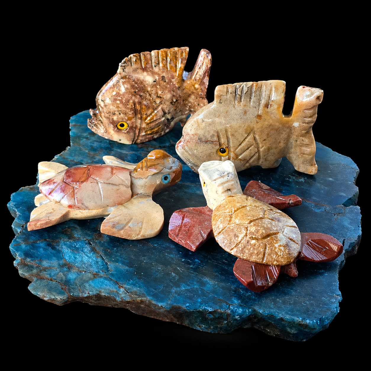 Apatite and steatite marine animal carving lot with two fish and two turtles on a blue Madagascar apatite base, angled front detail view