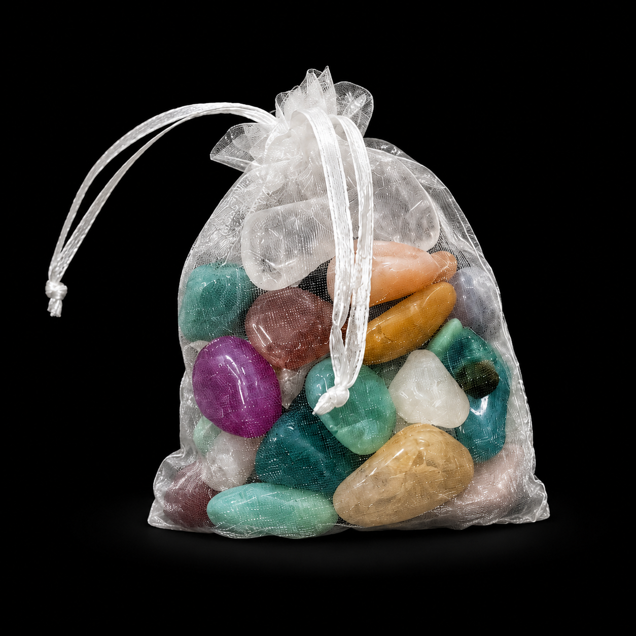 White organza drawstring bag filled with assorted polished tumbled mineral stones in mixed colours on a black background | HeyMiner