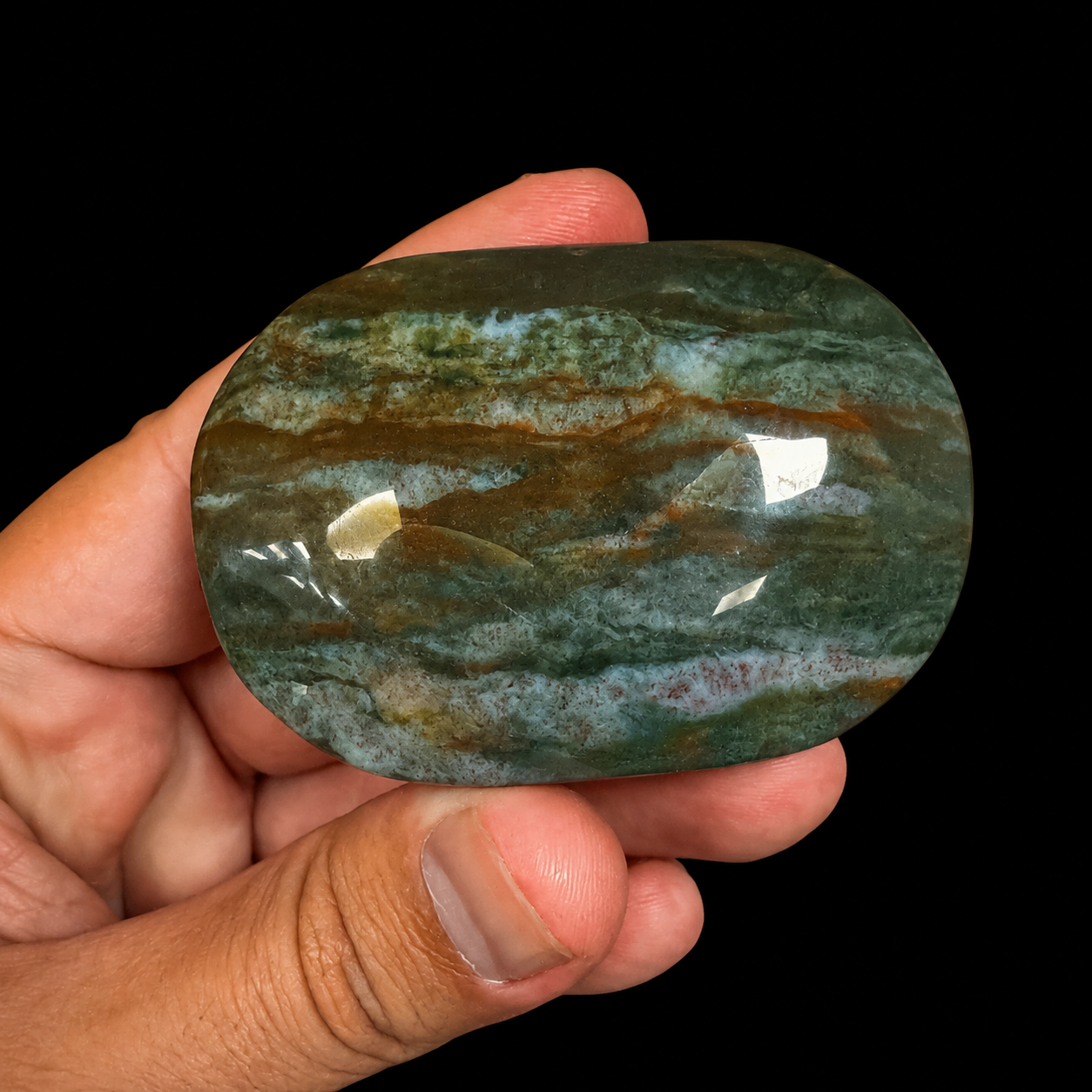 Ocean Jasper XL palm stone held in hand, front view, polished green mineral soap stone with blue-green bands and earthy brown natural pattern | HeyMiner
