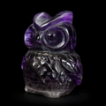 Opposite angled side view of a purple fluorite owl carving showing natural bands, polished surface and carved owl features