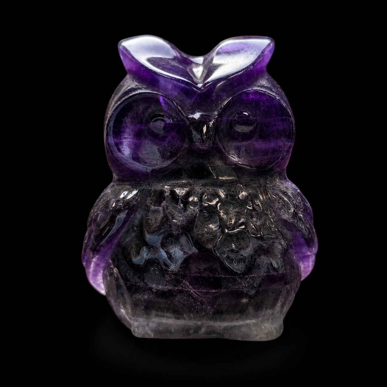 Front view of a polished purple fluorite owl carving with rounded eyes, natural banding and translucent smoky detail